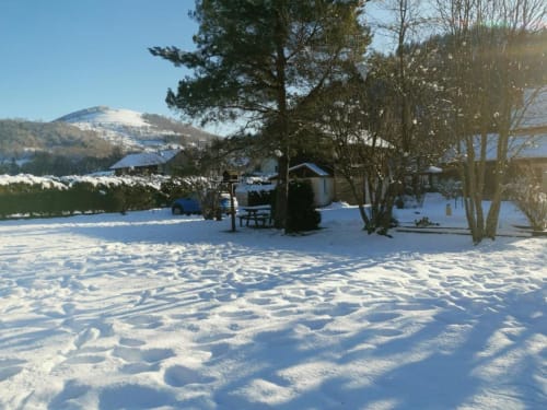 Jardin enneigé du gîte Les Grandes Voies au Ménil avec vue sur les montagnes et mobilier de jardin