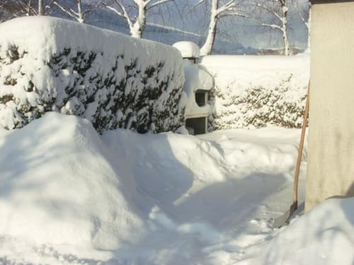 Vue hivernale du jardin du Chalet Cossu aux Gîtes les Grandes voies au Ménil, avec sapins enneigés et montagnes