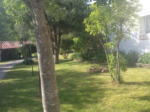 Les beaux jardins des Gîtes les Grandes voies avec arbres matures, pelouse verdoyante et bâtiments de charme au Ménil