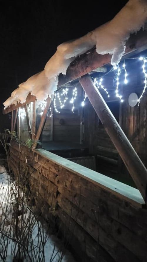 Snowy roofline with twinkling icicle lights on cottage terrace at night, Gîtes les Grandes Voies