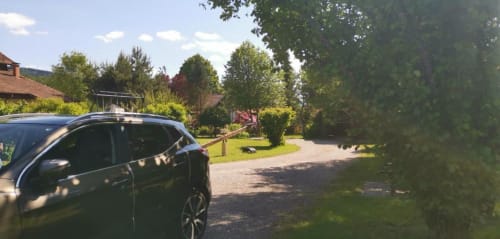 SUV noir garé aux Gîtes les Grandes voies au Ménil, allée ombragée avec vue sur le jardin