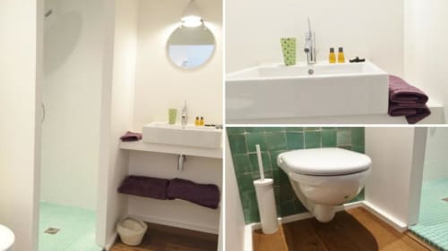 Salle de bains moderne au Gîte Denis & Virginie Versailles avec lavabo blanc, toilettes murales, carrelage vert et serviettes