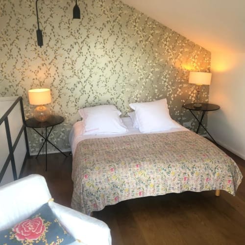 Chambre cosy de l'appartement-studio Denis & Virginie à Versailles avec papier peint floral, oreillers blancs et lampes vue jardin.