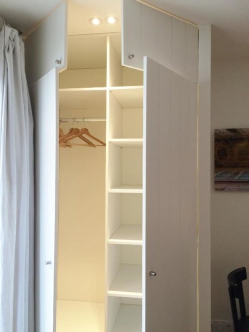 Dressing moderne avec étagères éclairées et cintres en bois dans l'appartement Denis & Virginie à Versailles