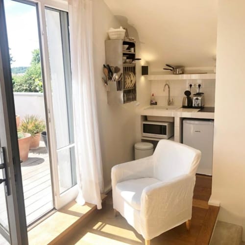 Kitchenette et coin séjour du studio à Versailles avec accès à la terrasse et vue sur le jardin