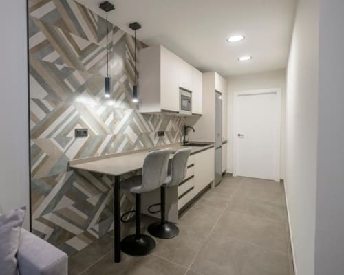 Cocina moderna en ML Apartments Valencia con azulejos geométricos, barra americana y gabinetes blancos