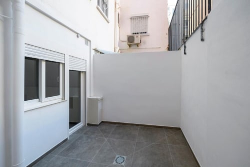 Terraza moderna de apartamento en ML Apartments Valencia con paredes blancas, puertas corredizas de vidrio y suelo de azulejos oscuros