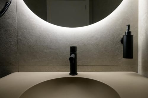Moderno lavamanos con grifo negro y dispensador de jabón en ML Apartments Valencia, con espejo redondo iluminado y