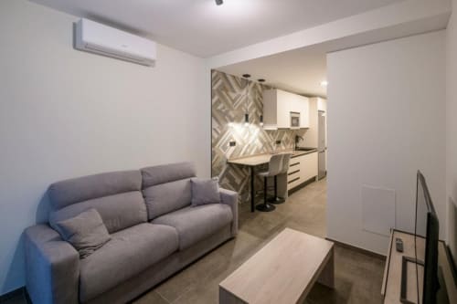 Sala de estar moderna en ML Apartments, Valencia: sofá gris, cocina abierta y azulejos geométricos