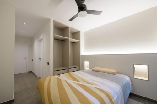 Dormitorio moderno en ML Apartments Valencia con cama queen, armarios empotrados, ventilador de techo y decoración neutral