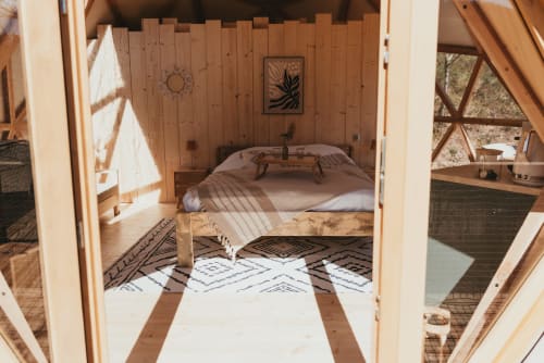 Interior of geodesic dome cottage at Les Cabanes du Nideck in Oberhaslach, France, with wooden walls, bed, and patterned rugs