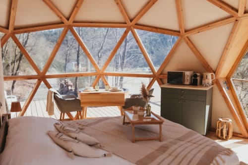 Geodesic dome bedroom at Les Cabanes du Nideck with wooden frame, bed, dining area, and forest mountain views in Oberhaslach,