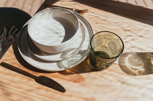 Nested ceramic bowls and decorative glass on wooden table at Les Cabanes du Nideck cottage in Oberhaslach