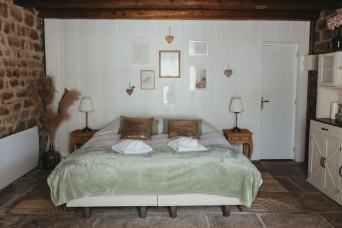 Cozy cottage bedroom at Les Cabanes du Nideck with double bed, wooden beams, and white shiplap walls
