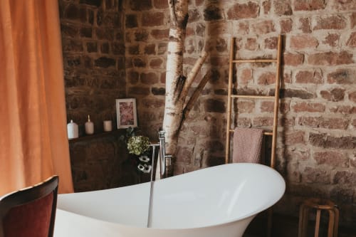 Modern white freestanding bathtub in rustic brick cottage bathroom at Les Cabanes du Nideck, Oberhaslach