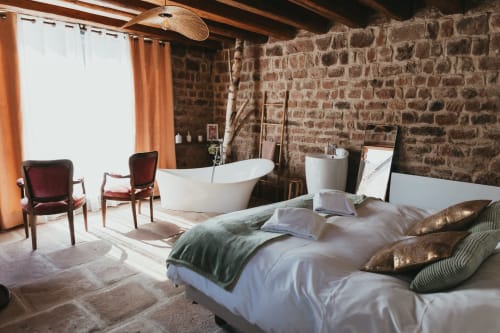 Luxurious bedroom with freestanding bathtub at Les Cabanes du Nideck, Oberhaslach cottage featuring exposed brick walls.