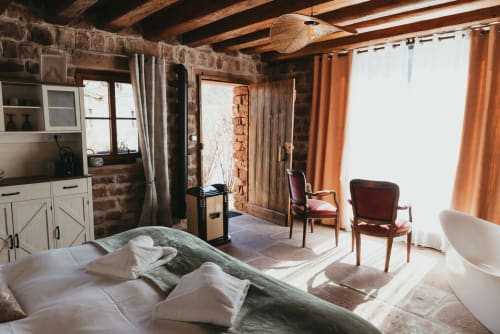 Rustic cottage bedroom at Les Cabanes du Nideck with exposed stone walls, wooden beams, and mountain views in Oberhaslach