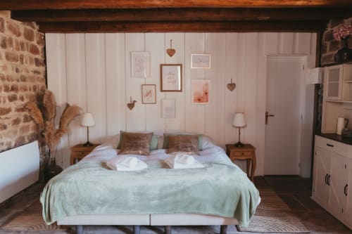 Cozy cottage bedroom at Les Cabanes du Nideck with double bed, wooden furnishings, and heart decorations on pink walls.