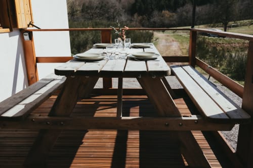 Outdoor picnic table set for dining on a wooden deck overlooking forest and mountains at Les Cabanes du Nideck, Oberhaslach