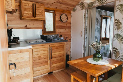 Cozy wooden cottage kitchen and dining area at Les Cabanes du Nideck, Oberhaslach, with rustic cabinetry, stove, and wooden