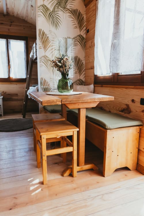 Wooden cottage interior at Les Cabanes du Nideck with dining table, chair, dried flowers in green vase, and palm leaf