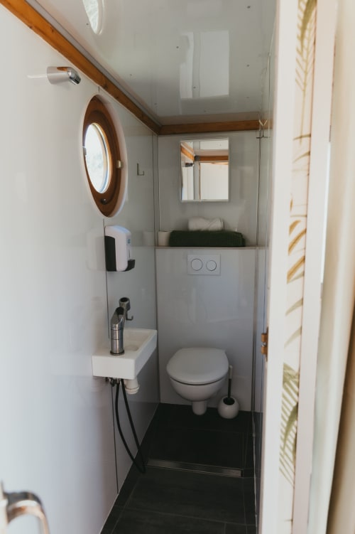 Modern bathroom in La Roulotte cottage at Les Cabanes du Nideck, Oberhaslach, featuring compact toilet, sink, and wooden