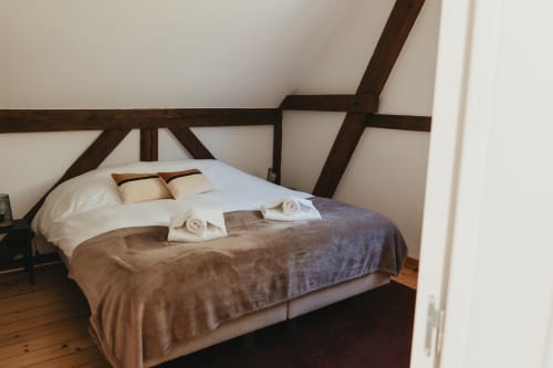 Cozy bedroom in Le Petit Chalet cottage at Les Cabanes du Nideck, Oberhaslach, with exposed wooden beams and warm bedding