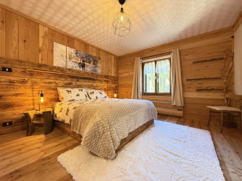 Cozy wooden chalet bedroom in Auronzo di Cadore with queen bed, mountain views, and rustic Alpine decor