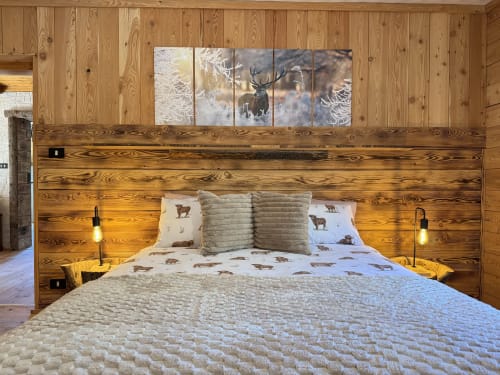 Rustic wooden bedroom in Alpine chalet near Auronzo di Cadore with deer-themed bedding and mountain view artwork