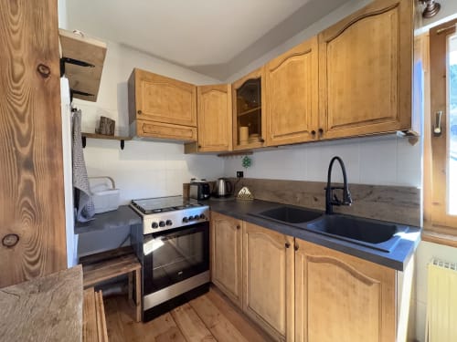 Wooden chalet kitchen with gas stove, dark countertop, sink, and white tile backsplash in Auronzo di Cadore mountain