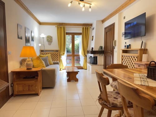 Luminosa zona living in Auronzo di Cadore con arredamento in legno, dettagli gialli, TV e vista sulle montagne