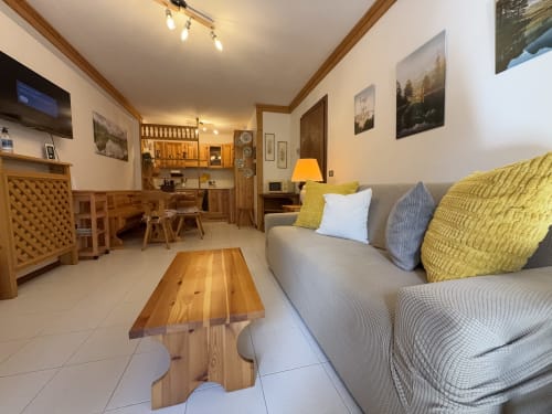 Accogliente soggiorno in un appartamento ad Auronzo di Cadore con divano grigio, cuscini gialli, mobili in legno e vista sulle montagne