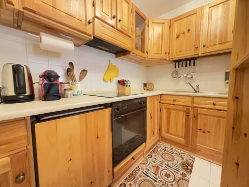 Cucina in legno con piano di lavoro bianco, forno nero e utensili da cucina nell'appartamento CIMABOSCO, Auronzo di Cadore