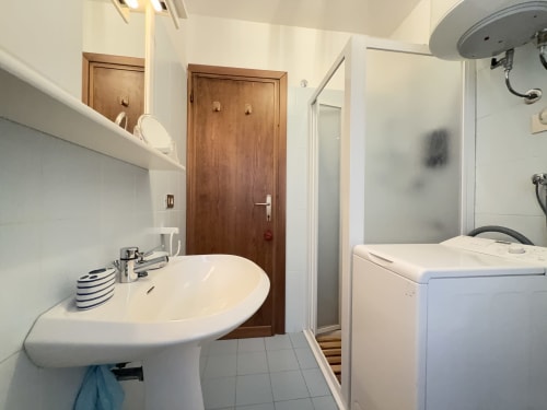 Moderno bagno con lavabo a colonna, box doccia e lavatrice nell'appartamento CIMABOSCO ad Auronzo di Cadore