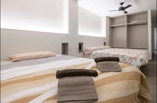 Amplio dormitorio en ML Apartments Valencia con múltiples camas, armarios empotrados, ventilador de techo e iluminación moderna