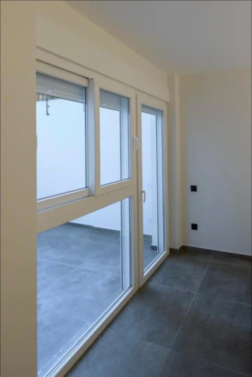 Balcón moderno con puertas correderas de vidrio en ML Apartments, Valencia, con suelo de baldosas oscuras y paredes color crema