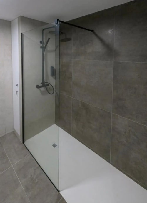 Moderno mampara de ducha en vidrio con paredes de azulejos gris oscuro y base blanca en baño de apartamento en Valencia