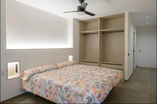 Moderno dormitorio en ML Apartments Valencia con ropa de cama estampada colorida, armario empotrado, ventilador de techo e iluminación ambiente