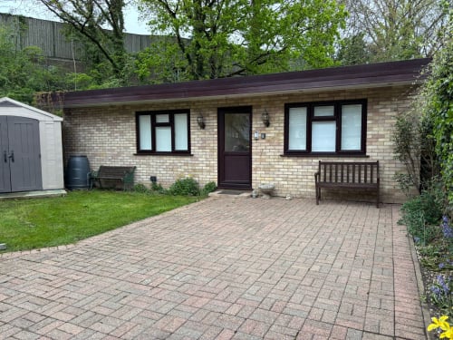 Detached brick villa in High Wycombe with paved courtyard, garden seating, and modern windows