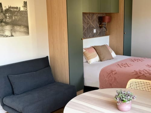 Studio aux Logis du canal avec canapé bleu, table en bois fleurie et lit aux draps rose à Betton