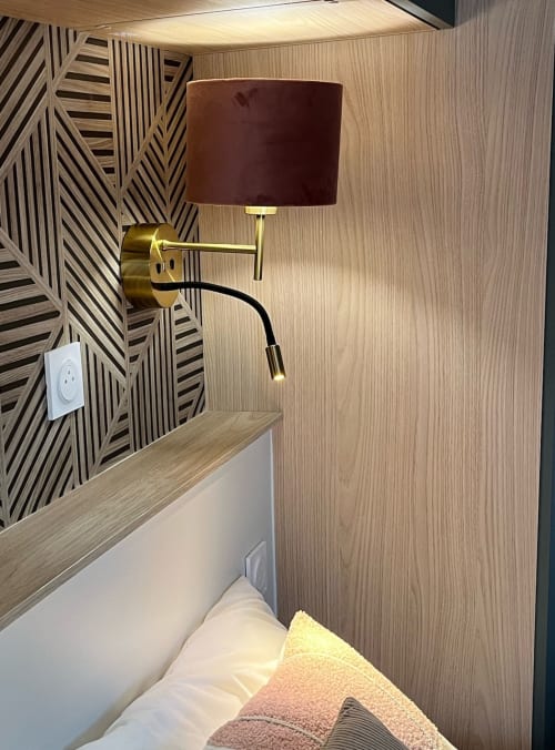 Chambre moderne Les logis du canal avec applique murale dorée, abat-jour bordeaux et mur accent géométrique en bois