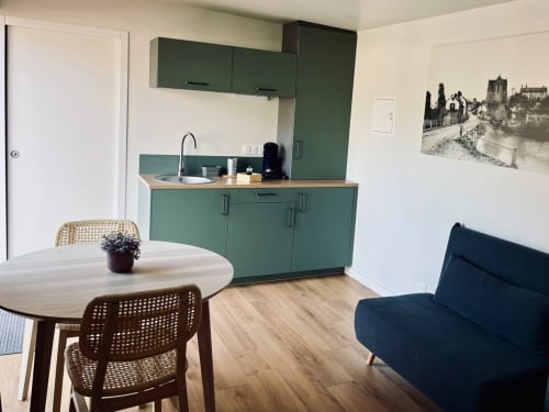 Kitchenette moderne aux armoires vertes, table à manger et canapé anthracite aux Logis du canal, Betton