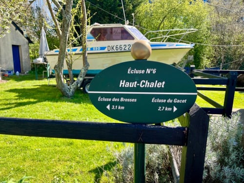 Enseigne Haut-Chalet aux Logis du Canal à Betton avec bateau amarré et indications de chemin de halage