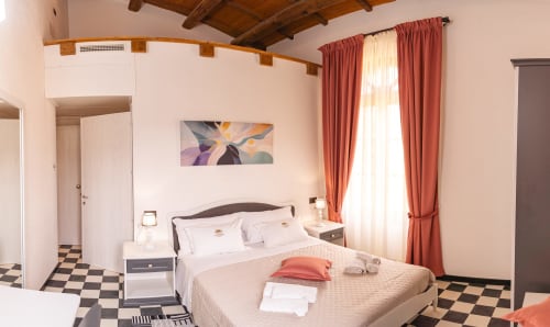 Spaziosa camera doppia all'Albergo Al Cinghiale con comfort moderni, tende rosse e pavimento a quadri