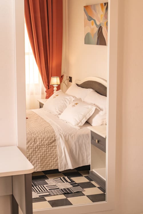 Camera doppia moderna presso l'Albergo Al Cinghiale con biancheria bianca, tende arancioni e opere d'arte contemporanea
