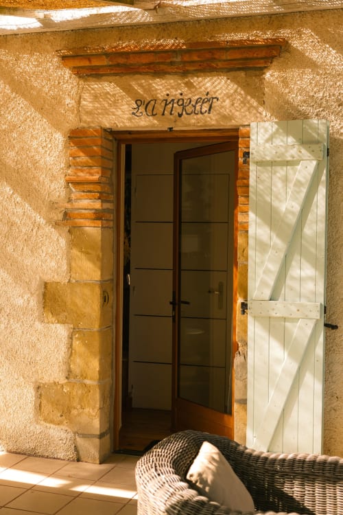 Entrée du Gîte de Langelet au Domaine Langelet, Saint-Gauzens, avec porte en bois foncé et volets blancs