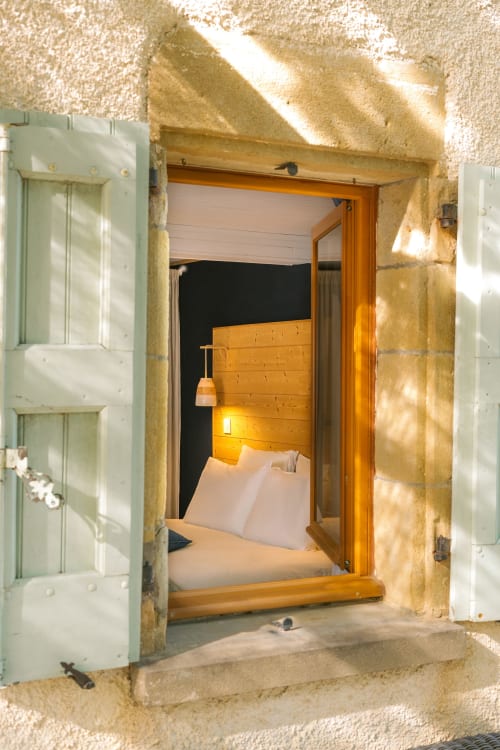 Entrée cosy de la chambre au Gîte de Langelet à Saint-Gauzens avec lit en bois et éclairage chaleureux