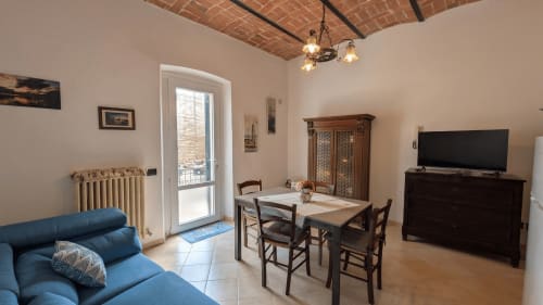 Accogliente soggiorno con divano blu, tavolo da pranzo, TV a schermo piatto e accesso al balcone di Villa Italia