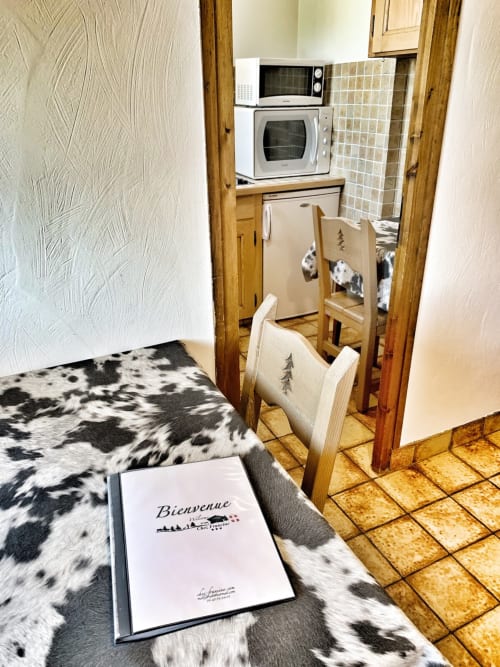 Studio apartment at Chez Francine with welcome folder on bed, kitchenette, microwave, and laundry facilities visible