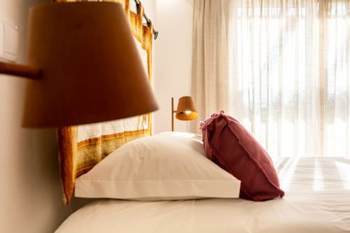Quarto luminoso na Pousada Cerro da Campaniça em Santiago do Cacém com roupa de cama branca, almofada bordô, cabeceira de madeira e